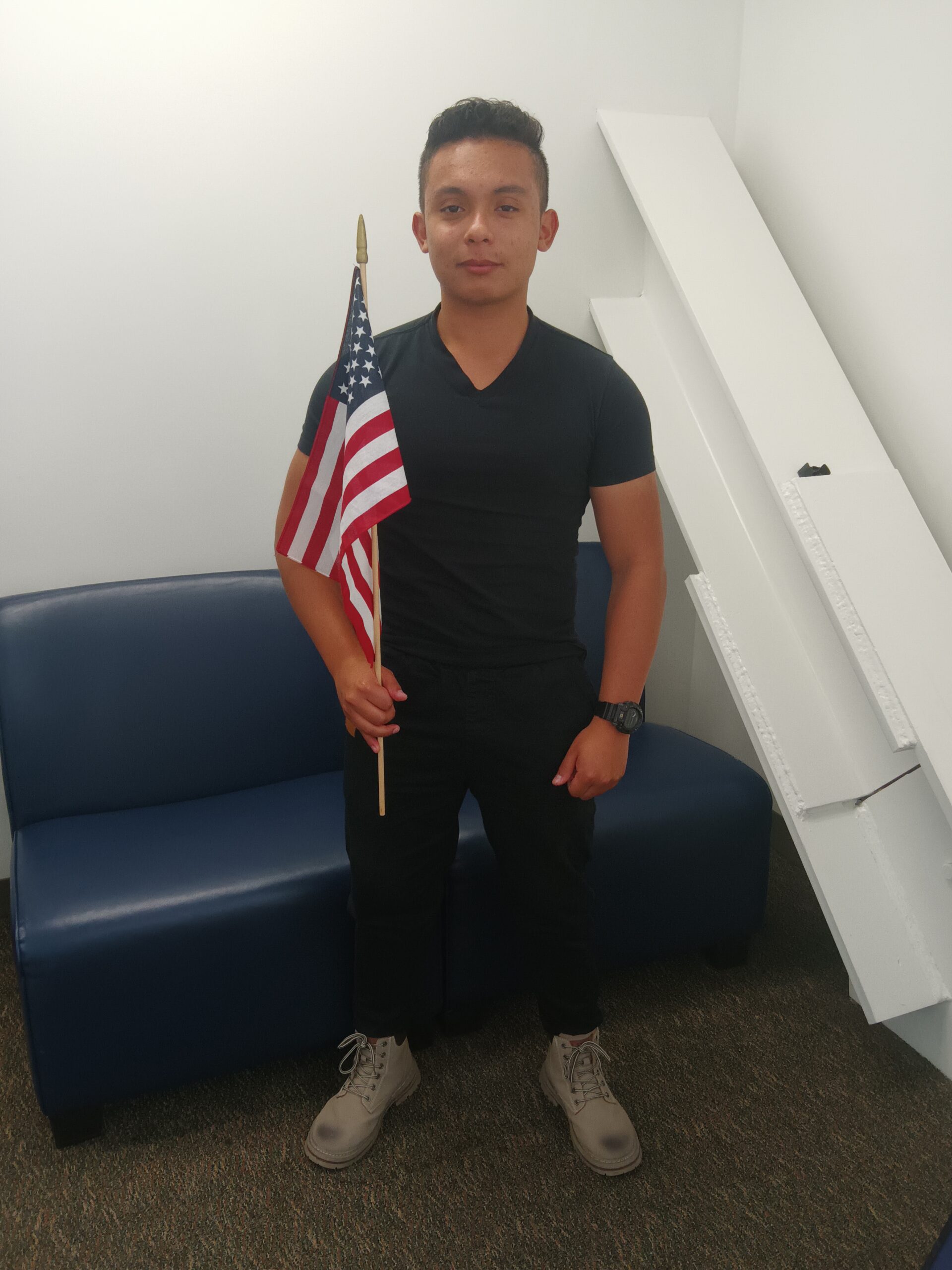Photo of a young man with a flag in a white room.