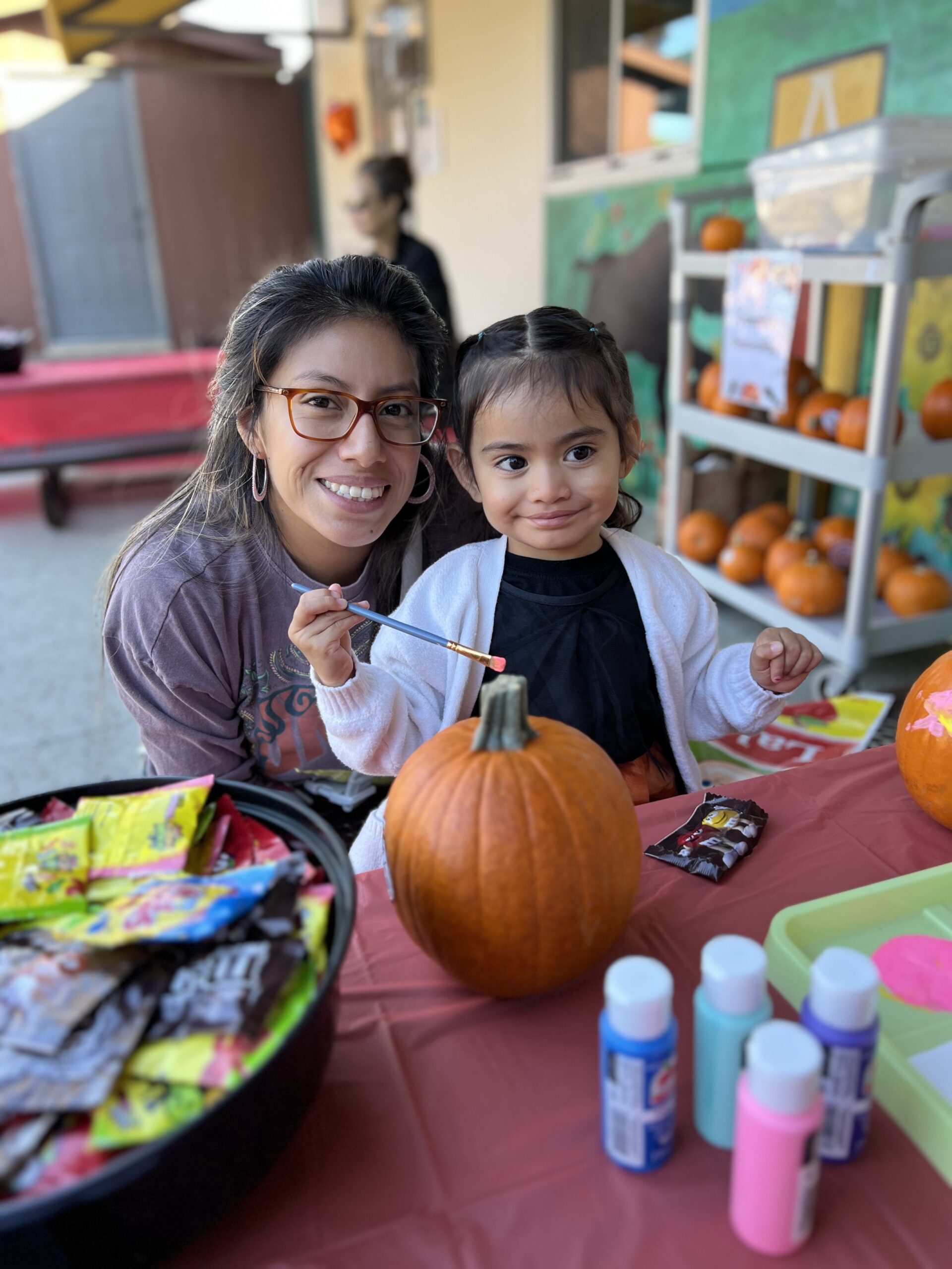 Photo of a mom and daughter doing arts and crafts with a pumpkin.