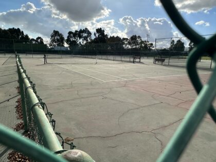 Photo of tennis court through fence.