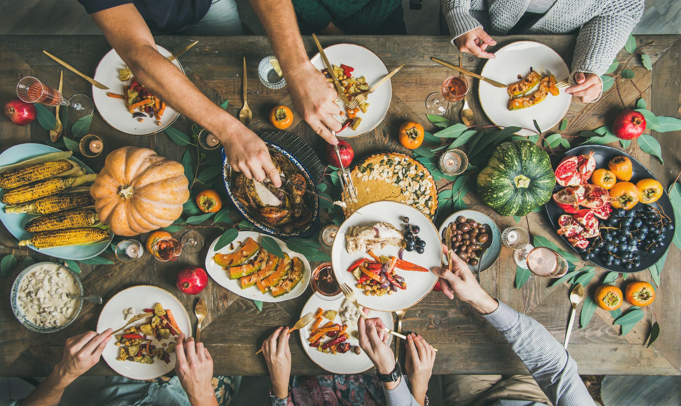 Top down photo of many hands sharing plates of food.