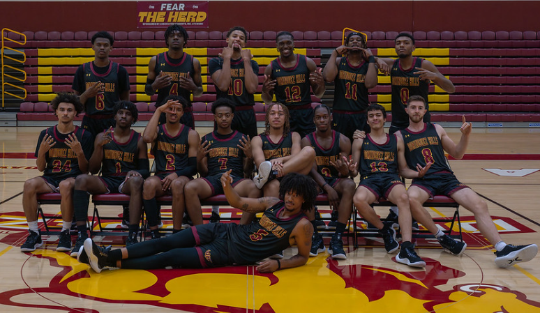 Group photo of a men's basketball team in a gym with black jerseys.