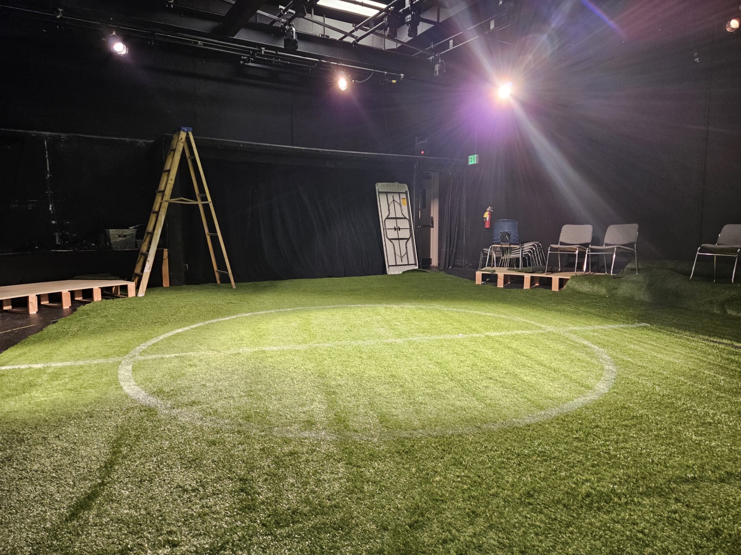 Photo of the set of a play with a realistic astroturf stage.