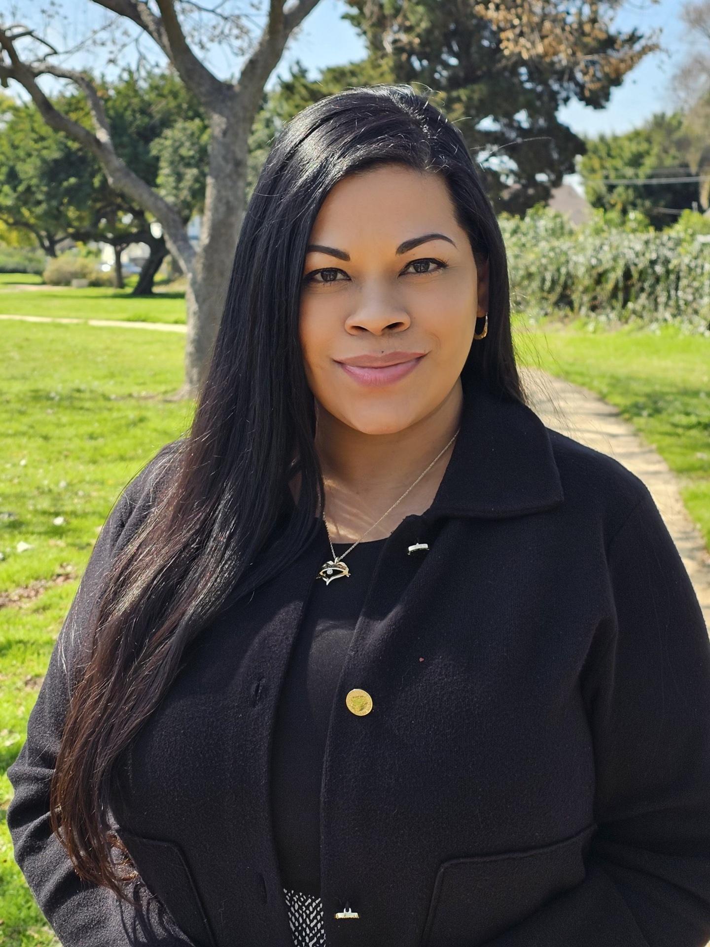 Photo of woman in a black blazer in a field.