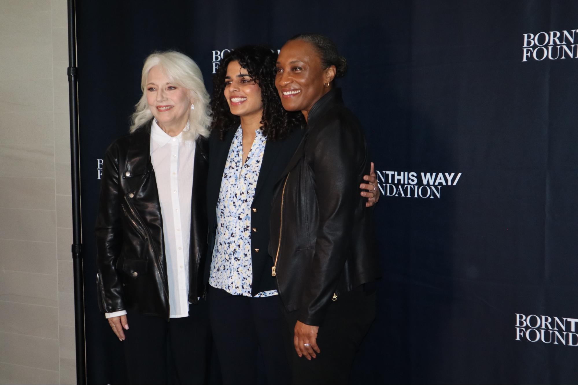 Photo of three people standing in front of a black backdrop at an event.