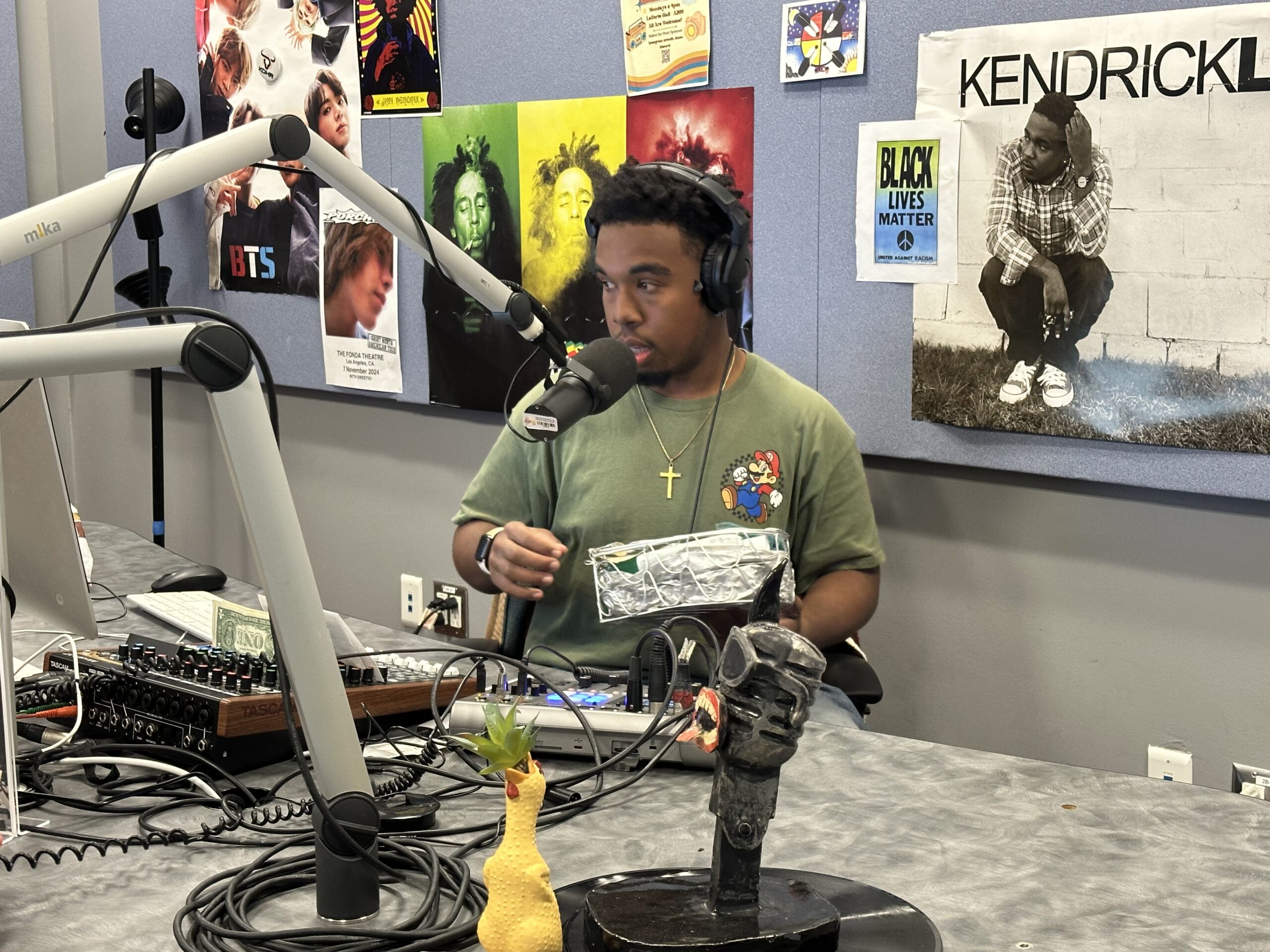 Immanuel Tims speaks into a microphone while hosting his student-run game show Person, Place, or Thing in the KDHR radio studio.