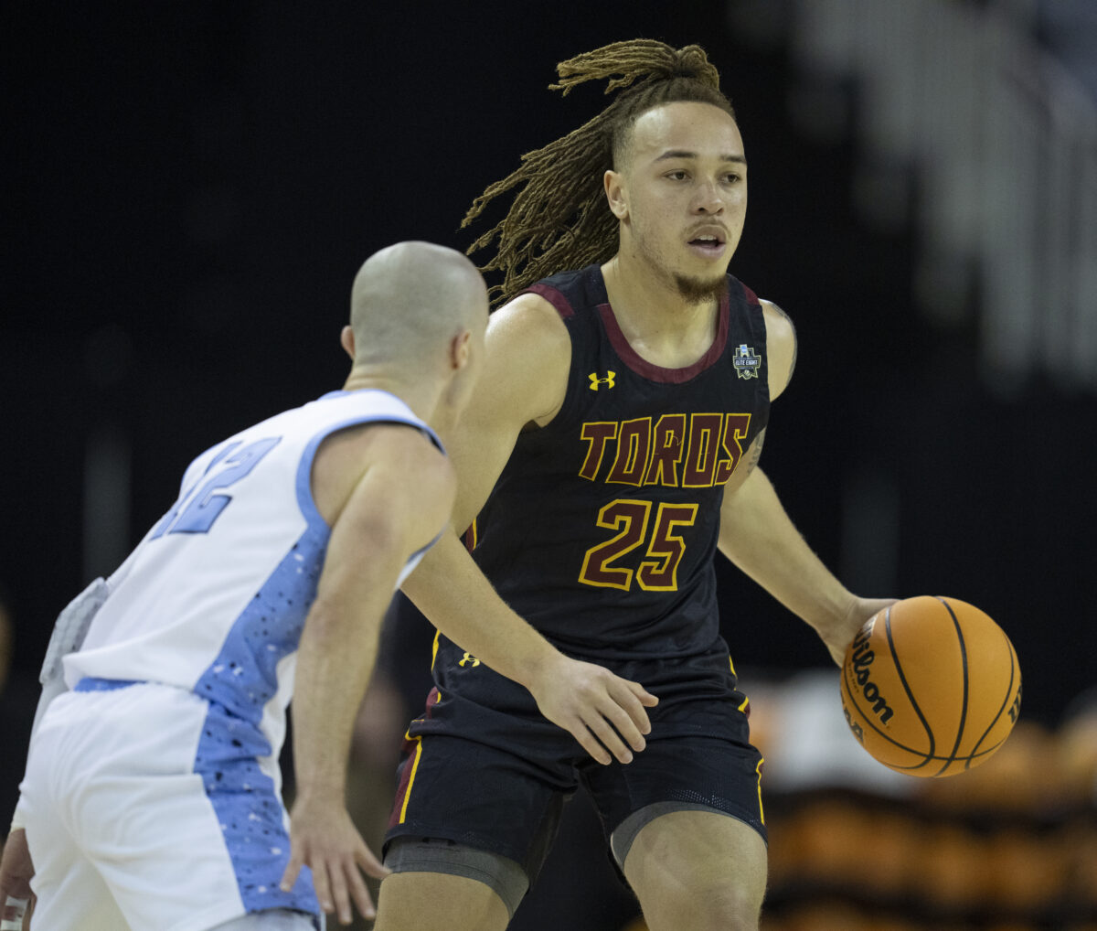 A CSUDH men’s basketball player wearing jersey number 25 dribbles the ball while being guarded by a defender during a game.