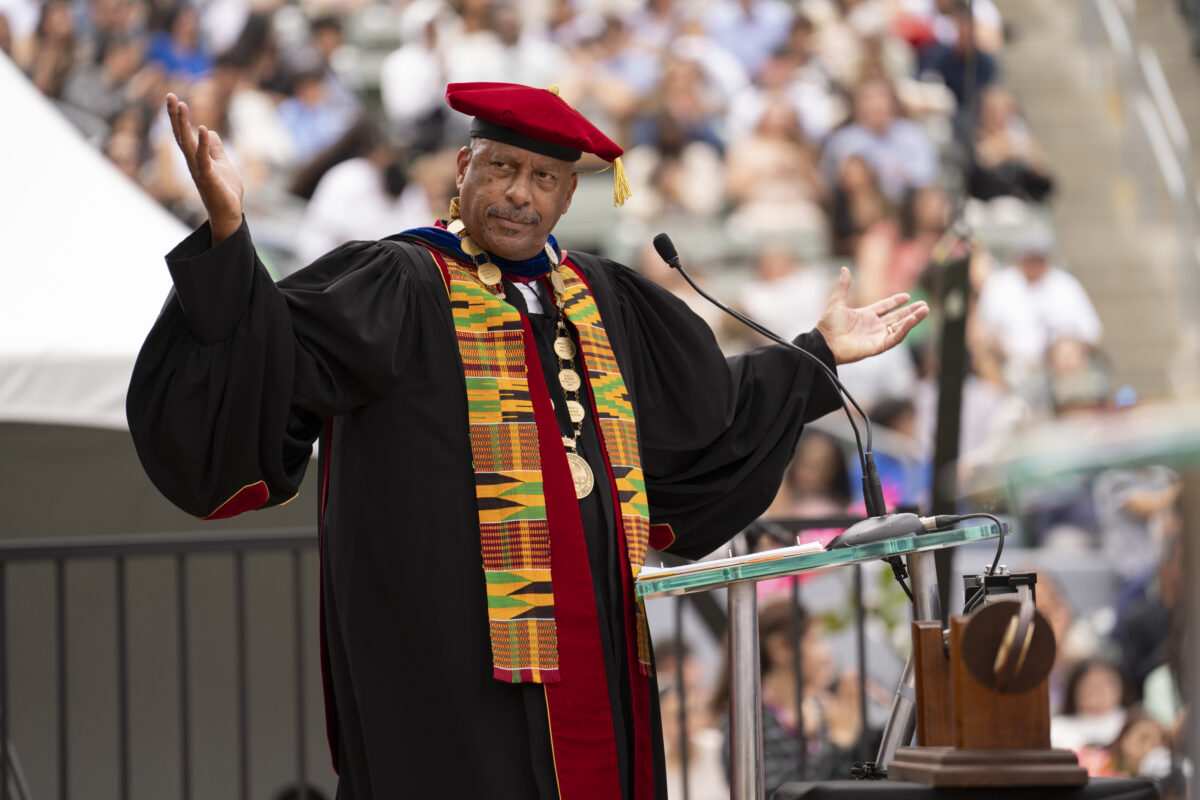 CSUDH President Thomas A. Parham wears graduation regalia while standing at a podium at Spring Commencement ceremony.